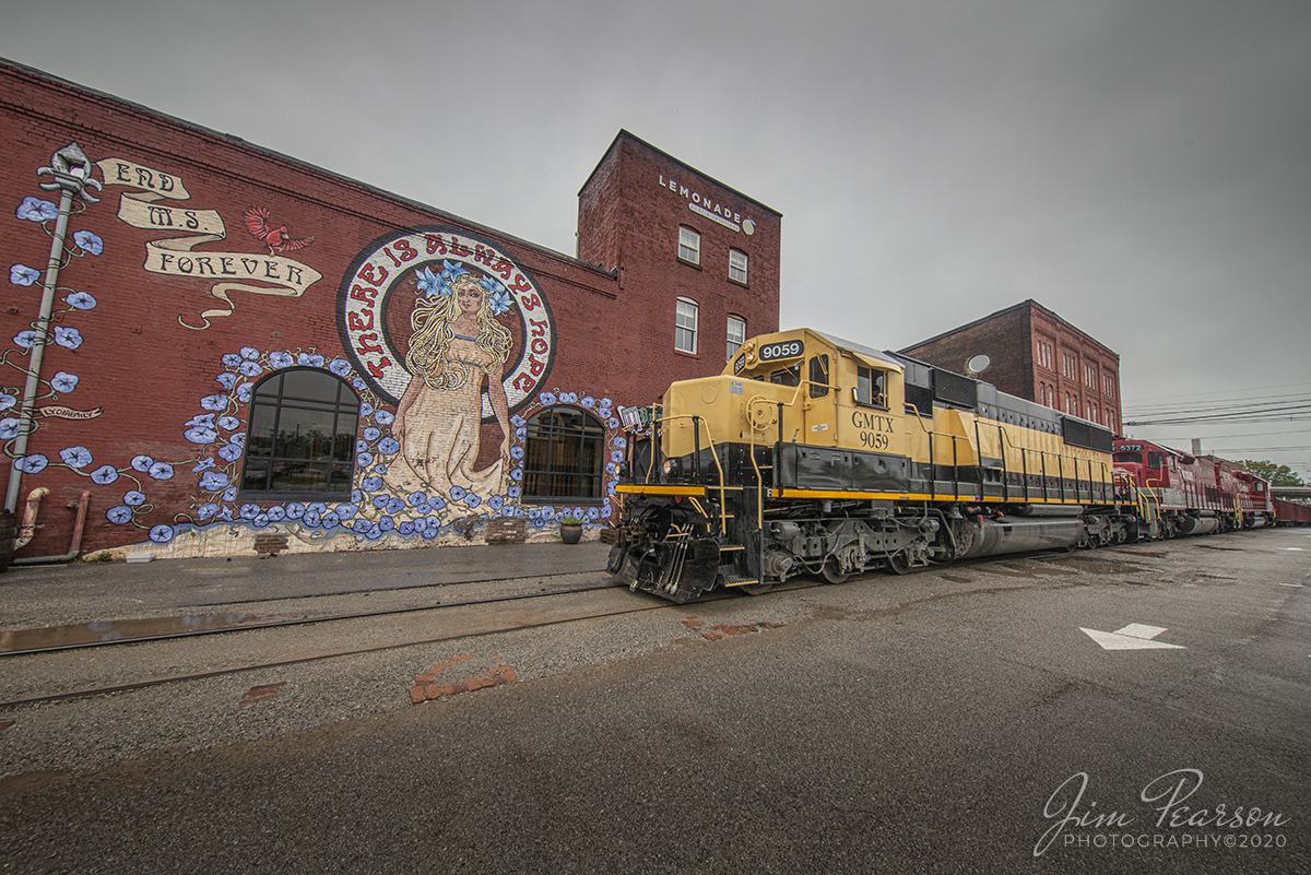 May 8, 2020 – RJ Corman’s empty sand train Z543-07 heads north with GMTX 9059 (SD60) leading as it passes through the area of Louisville, Kentucky known as Butchertown. It was returning to Nugent Sand Company for another load of sand for Lexington, Ky  and a variety of central Kentucky customers. Normally this train runs during the early morning darkness, but lately it has been making daylight runs on Fridays.

The Nugent Sand Co. takes a million tons of sand out of the Ohio River each year. Some 400,000 to 600,000 tons of that has been moved by R.J. Corman into the Lexington and surrounding markets each year since the two companies partnered in 2005.

GMTX 9059 was originally built in 1986 as an EMD lease/demo unit and most recently It was running on the New York and Susquehanna & Western Railway (NYSW), Headquartered in Cooperstown, New York, where it was painted in their scheme. It was leased to them by GMTX and is now it is being run on RJC after NYSW decided it did not meet NYSW standards. RJC has a contract with GMTX to do testing and maintenance on their locomotives and are doing so with this unit currently.