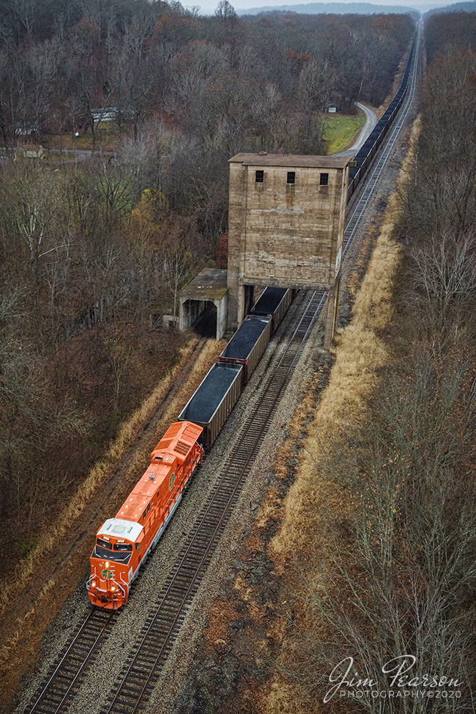 CN Elgin Jolliet Heritage Unit

Canadian National 3023, the new Elgin Jolliet Heritage unit, (EJ&E) leads loaded coke train U700 under the old Illinois Central coaling tower, left over from the steam era, as it heads south on CNs Bluford subdivision on a misty overcast day on CNs Bluford Subdivision at Reevesville, Illinois.

According to a press release from CN: This is one of five locomotives representing the railways that have joined their team since their privatization, 25 years ago. Each one features the colors of the railway at the time it merged with CN as well as the logo specially created to commemorate the quarter century of our IPO. These acquisitions propelled our service farther than any other North American railway, similar to our IPO propelled CN to new heights. The engines release so far are BC Rail; Grand Trunk West; CN; Illinois Central; Wisconsin Central; and Elgin, Joliet & Eastern.

According to Wikipedia: A coaling tower, coal stage or coaling station was a facility used to load coal as fuel into railway steam locomotives. Coaling towers were often sited at motive power depots or locomotive maintenance shops.

Coaling towers were constructed of wood, steel-reinforced concrete, or steel. In almost all cases coaling stations used a gravity fed method, with one or more large storage bunkers for the coal elevated on columns above the railway tracks, from which the coal could be released to slide down a chute into the waiting locomotives coal storage area. The method of lifting the bulk coal into the storage bin varied. The coal usually was dropped from a hopper car into a pit below tracks adjacent to the tower. From the pit a conveyor-type system used a chain of motor-driven buckets to raise the coal to the top of the tower where it would be dumped into the storage bin; a skip-hoist system lifted a single large bin for the same purpose. Some facilities lifted entire railway coal trucks or wagons. Sanding pipes were often mounted on coaling towers to allow simultaneous replenishment of a locomotives sand box.

As railroads transitioned from the use of steam locomotives to the use of diesel locomotives in the 1950s the need for coaling towers ended. Many reinforced concrete towers remain in place if they do not interfere with operations due to the high cost of demolition incurred with these massive structures.

Tech Info: DJI Mavic Mini Drone, JPG, 4.5mm (24mm equivalent lens) f/2.8, 1/160, ISO 200.