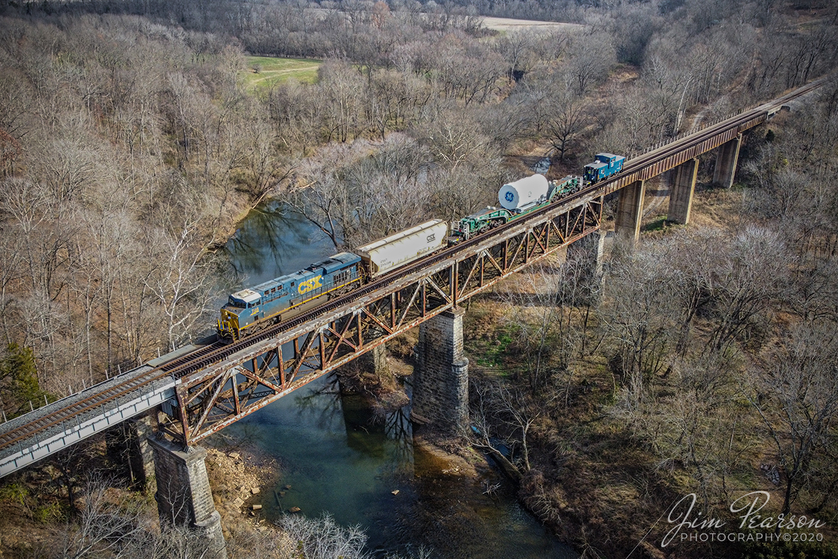 Northbound high and wide load at Red River

CSX W991-29 heads north on the Henderson Subdivision across the Red River bridge at Adams, Tennessee on December 5th, 2020 with a High and Wide load for General Electric at a steady 25mph.

The GE high and wide load is carried on GECX 021155 a Heavy load, 16-axle, depressed center flat car, which is owned by General Electrical Gas Turbine division. The car is 147 feet 10 inches long and the load deck length is 38 feet according to what I find on the web. It Was built in May of 1995 and is used to transport heavy gas turbines built by General Electric. A Kasgro Rail Corporation (KRL) caboose 072 brings up the rear with a full crew. The caboose and engine crews kept a close eye on clearances as they made their way north! 


Tech Info: DJI Mavic Mini Drone, JPG, 4.5mm (24mm equivalent lens) f/2.8, 1/400, ISO 100.