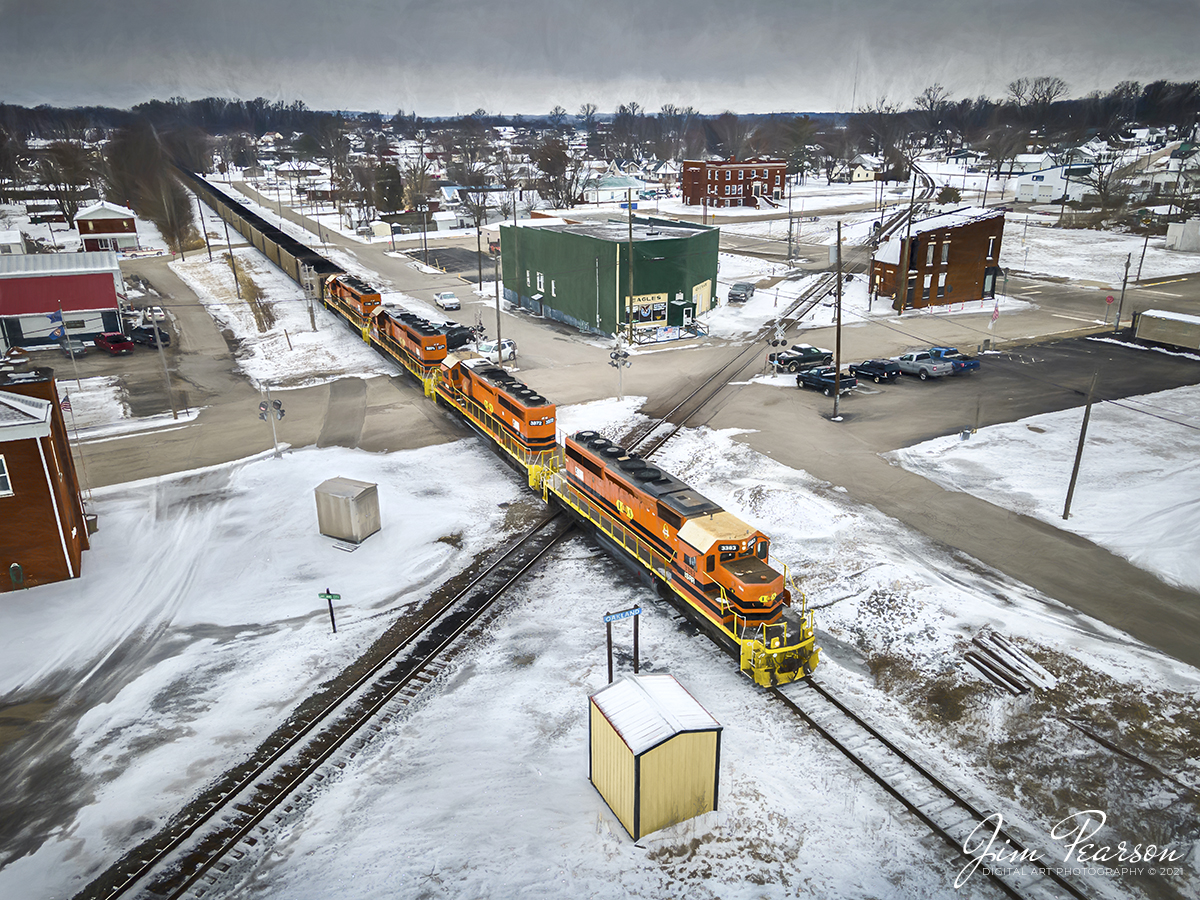 Digital Photo Art - Indiana Southern Railway pulls a Indiana Power and Light load of coal northbound at Oakland City, IN.

Another load of black coal crosses over the Norfolk Southern east-west line as Indiana Southern Railroad (ISRR) 3383, 3372, 3371 and 3386 lead their train north on their Petersburg Subdivision at Oakland City, Indiana on a very cold February 13th, 2021.

They will continue their move for another 20-30 miles or so through the freezing snow and ice to the Indiana Power and Light power plant at Petersburg, Indiana. As they repeat this run 3-6 times a week from Peabody's Wildboar Mine in Lynnville, IN.

According to Wikipedia: The Indiana Southern Railroad (reporting mark ISRR) is a short line or Class III railroad operating in the United States state of Indiana. It began operations in 1992 as a RailTex property, and was acquired by RailAmerica in 2000. RailAmerica was itself acquired by Genesee & Wyoming in December 2012.

Indiana Southern Railroad operates 186 miles of track from Indianapolis to Evansville. From Mars Hill (a neighborhood on the southwest side of Indianapolis) southwest through Martinsville and Spencer to Bee Hunter in Greene County, the ISRR runs on tracks that once made up the majority of the former Indianapolis & Vincennes Branch of the Pennsylvania Railroad. State Route 67 parallels the ISRR along much of this section. From Bee Hunter to Elnora the ISRR has trackage rights over the Indiana Rail Road. ISRR tracks resume from Elnora through Washington in Daviess County, Petersburg in Pike County, Oakland City in Gibson County, Elberfeld in Warrick County and Daylight in Vanderburgh County before terminating in Evansville along the former New York Central's Evansville & Indianapolis Branch.

#trainphotography #railroadphotography #trains #railways #dronephotography #jimpearsonphotography 

Tech Info: DJI Mavic Air 2 Drone, RAW, 4.5mm (24mm equivalent lens) f/2.8, 1/500, ISO 100.