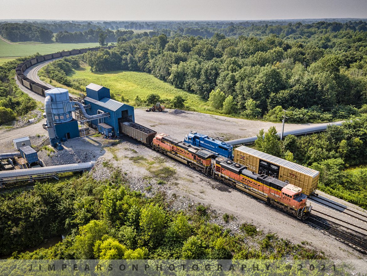 BNSF Coal unloads at Four Rivers Marine Terminal at West Paducah, KY

BNSF 8875 and 5913 lead a loaded coal train through the loop at 4 Rivers Terminal at West Paducah, Kentucky as the terminals unit GMTX 2144 sits in a house track during the operation on July 23rd, 2021. 

Four Rivers Marine Terminal (FRT) is owned by SCH Services, LLC, and located at West Paducah, KY at Ohio River mile marker 943. Four Rivers has an annual throughput capacity of 10 MM tons. Illinois Basin and Powder River Basin coals are transferred from railcar to barge here. 

According to SCH Services Website: It is primarily designed as a direct train-to-barge transfer terminal, FRT offers its customers an unparalleled combination of access to major waterways and multiple Class I railroads.  Our connection to the Paducah and Illinois Railroad gives FRT direct access to the BNSF, CN, and PAL railroads.  Considering only the modern Olmsted Lock and Dam separates the terminal from the Mississippi River, FRT presents a unique option for rail-bound shipments destined for both southeastern customers and export through New Orleans.  Four Rivers Terminal boasts a double, 150-car rail loop, coupled with a material handling system capable of transloading 4,000 tons of dry bulk material per hour.

Tech Info: DJI Mavic Air 2 Drone, RAW, 4.5mm (24mm equivalent lens) f/2.8, 1/640, ISO 100.