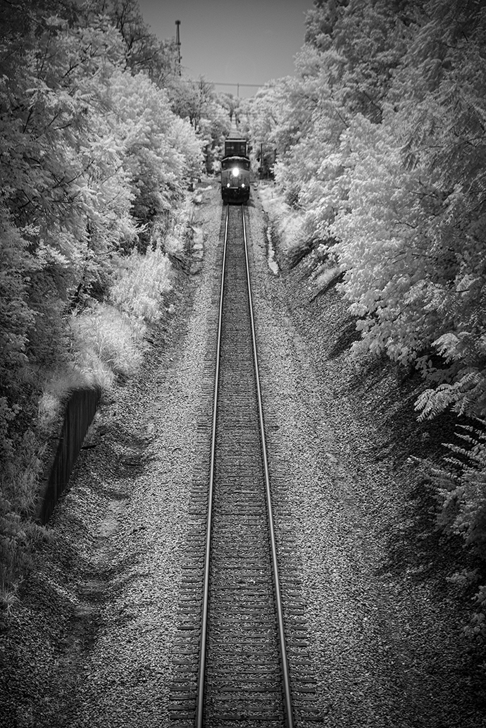 CSX Q028-28 northbound at Madisonville, Ky on the Henderson Subdivision

In this Infrared shot from July 29th, 2021 we catch CSXT 3250 as it leads Q028-28 north, approaching the North Main Street overpass at Madisonville, Ky on the Henderson Subdivision. 

I purposely chose to capture this train a bit further back in the frame as I really like the leading lines from the tracks, and it being surrounded by trees in the traditional infrared white! I did use a bit of vignette, as I do on most of my images, to help draw the eye and focal point to the subject of the photo.

Tech Info: Fuji XT-1, RAW, Converted to 720nm B&W IR, Fuji 18-55 @55mm, f/5, 1/500, ISO 200.