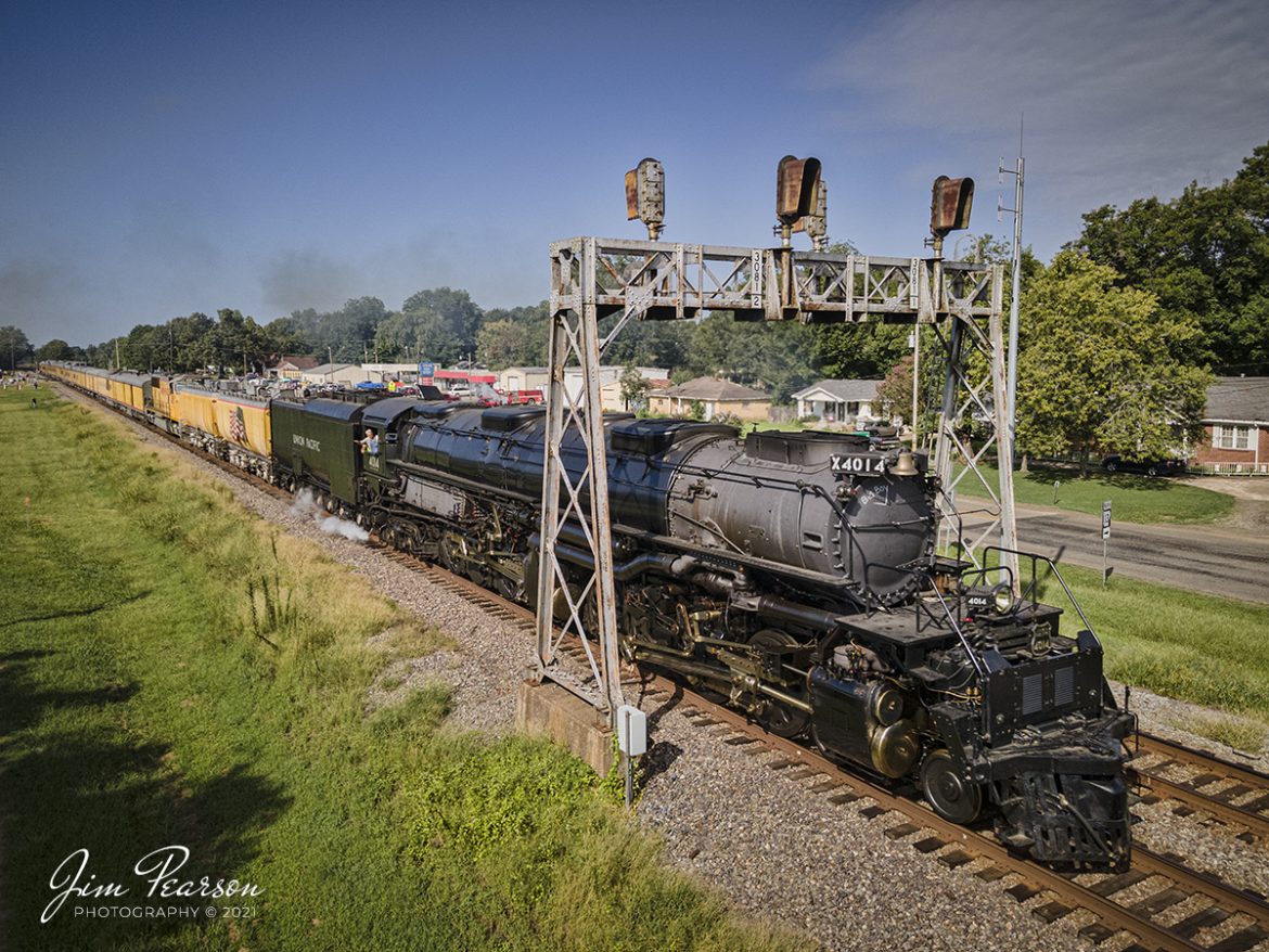 This is one of the last images from my DJI Air 2 drone before it ended up in the top of a 30' oak tree the next day at Dexter, MO after a Fly Away. 

In this shot Engineer Ed Dickens waves from the cab as Union Pacific's 4014, the Big Boy, passes under the signal bridge in downtown McRae, Arkansas on Friday, on August 27th, 2021, as they head north on the UP Hoxie subdivision on its way to Popular Bluff, AR.

The Big Boy is an articulated 4-8-8-4 steam locomotive which was manufactured by the American Locomotive Company (ALCO) of Schenectady, New York in 1941. There were a total 25 of these giants built and of the eight remaining locomotives this is the only operational one. 

According to Wikipedia: "The locomotive operated in revenue service until 1959, when it was donated to the Railway and Locomotive Historical Society in late 1961 and thereafter displayed in Fairplex at the RailGiants Train Museum in Pomona, California. 

In 2013, UP re-acquired the locomotive and launched a restoration project at their Steam Shop in Cheyenne, Wyoming. In May 2019, No. 4014 was operated for the first time after sitting dormant for almost six decades. 

It ran its first excursion, double-headed with Union Pacific 844, three days later on May 4, 2019. Now part of the Union Pacific's heritage fleet, it now operates in excursion service, in addition to hauling revenue freight during ferry moves."

The Big Boy is currently on a month-long tour around the Midwest through, Arkansas, Colorado, Kansas, Illinois, Louisiana, Missouri, Nebraska, Oklahoma, Texas, and Wyoming before heading home to Cheyenne, Wyoming on September 7th. For the route and schedule visit: https://www.up.com/heritage/steam/schedule/index.htm to see if it's stopping near you!

Tech Info: Wide Photo: DJI Mavic Air 2 Drone, RAW, 4.5mm (24mm equivalent lens) f/2.8, 1/800, ISO 100, August 27, 2021.