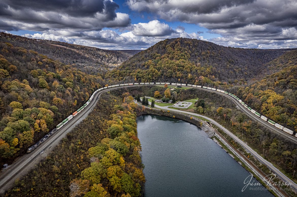 Norfolk Southern 4041 leads an intermodal through Horseshoe Curve at Altoona, Pennsylvania as it heads west on the NS Pittsburgh Line on a beautiful fall afternoon, on September 3rd, 2021.

According to Wikipedia: Horseshoe Curve is a three-track (though originally four) railroad curve on Norfolk Southern Railway's Pittsburgh Line in Blair County, Pennsylvania. The curve itself is about 2,375 feet long and 1,300 feet in diameter; it was completed in 1854 by the Pennsylvania Railroad as a way to lessen the grade to the summit of the Allegheny Mountains. It eventually replaced the time-consuming Allegheny Portage Railroad, the only other route across the mountains for large vehicles. Because of the Allegheny Mountains geoform, in and around Altoona - and almost perfectly at "The Curve" - westbound traffic goes south and eastbound traffic goes north. So, in terms of final destination, the southern side of "The Curve" is where trains leave to go west, and vice versa.

The rail line has been important since its opening, and during World War II the Curve was targeted by Nazi Germany in 1942 as part of Operation Pastorius. The Curve was later owned and used by Pennsylvania Railroad successors Penn Central, Conrail, and Norfolk Southern. Horseshoe Curve was added to the National Register of Historic Places and designated a National Historic Landmark in 1966, and it became a National Historic Civil Engineering Landmark in 2004.

Horseshoe Curve has long been a tourist attraction; a trackside observation park was completed in 1879. The Park was renovated and a visitor center built in the early 1990s. The Railroaders Memorial Museum in Altoona manages the center, which has exhibits pertaining to the curve.

Tech Info: DJI Mavic Air 2S Drone, RAW, 22mm, f/2.8, 1/500, ISO 100 -1 stop.