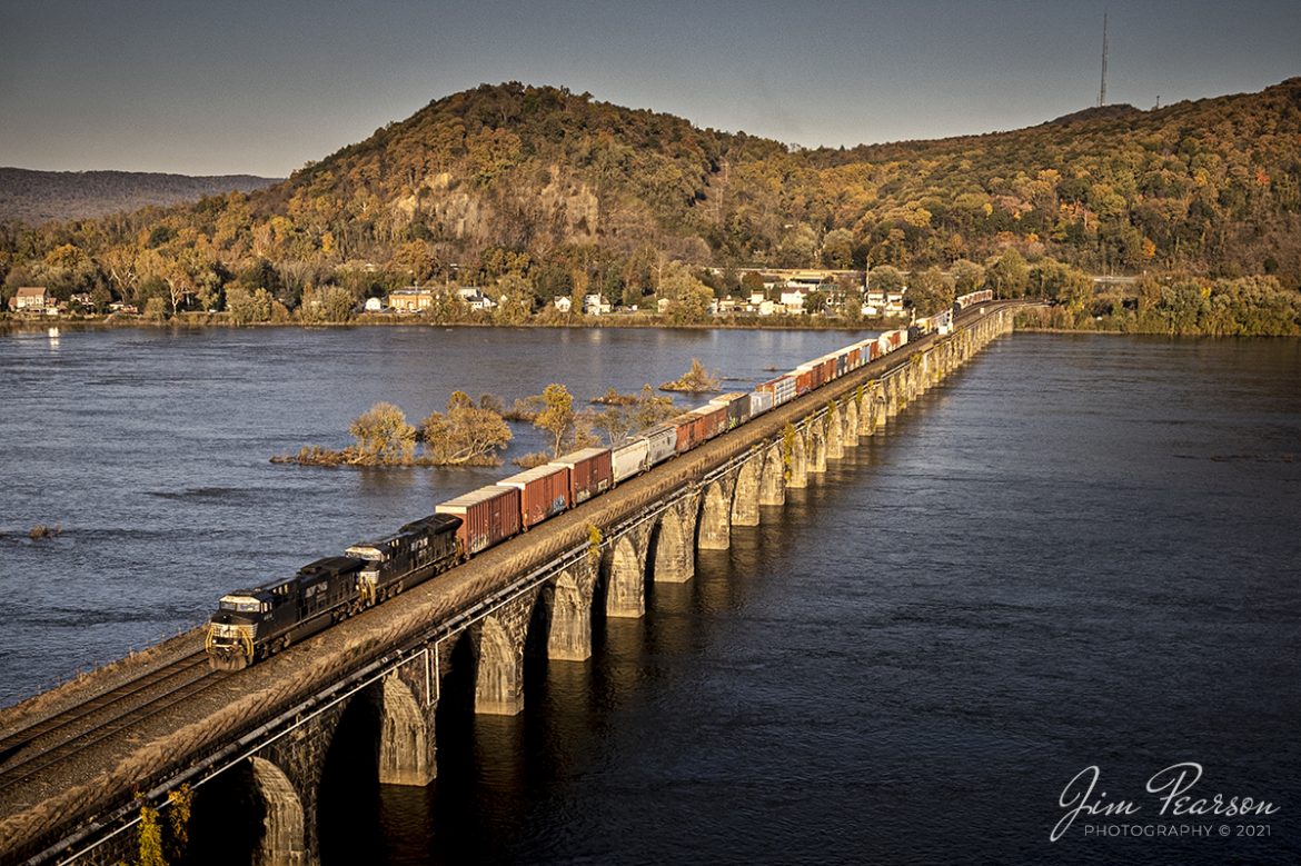 Norfolk Southern 4414 leads a freight train westbound across the Rockville Bridge over the Susquehanna River at Rockville, Pennsylvania on the NS Pittsburgh line as they head for Enola Yard at Enola, PA on November 5th, 2021.

According to Wikipedia: The Rockville Bridge is the longest stone masonry arch railroad viaduct ever built, with forty-eight 70-foot spans and a total length of 3,820 feet (1,160 m). The bridge crosses the Susquehanna River about 5 miles (8 km) north of Harrisburg, Pennsylvania. The eastern end is in Rockville and the western end is just south of Marysville. Completed in 1902 by the Pennsylvania Railroad, it remains in use today by the Norfolk Southern Railway and Amtrak's Pennsylvanian route.

The bridge was listed on the National Register of Historic Places in 1975 and was designated as a National Historic Civil Engineering Landmark in 1979.

The first bridge at the site was a one-track wooden truss. It opened on September 1, 1849, when the PRR began operating over it. The Northern Central Railway began to use it after abandoning their Marysville Bridge. It was replaced in 1877 with a double-track iron truss bridge.

The third and current bridge was built between April 1900 and March 1902 by Drake & Stratton Co., which built the eastern half, and H.S. Kerbaugh, working from the west. The laborers were Italian or local.

Control of the bridge passed to Penn Central after the PRR merger in 1968, then to Conrail and finally the Norfolk Southern. 

Tech Info: DJI Mavic Air 2S Drone, RAW, 22mm, f/2.8, 1/1000, ISO 100.

#trainphotography #railroadphotography #trains #railways #dronephotography #trainphotographer #railroadphotographer #jimpearsonphotography