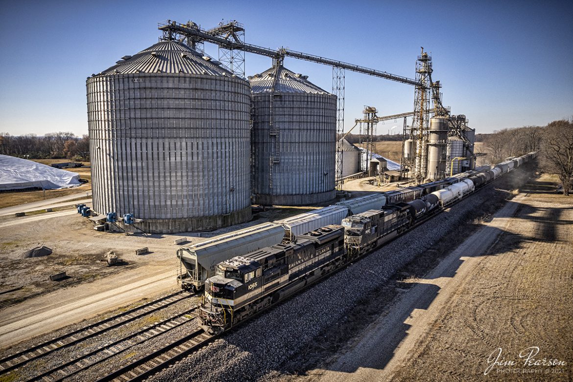 Norfolk Southern Savannah and Atlanta Heritage unit 1065 leads NS 167, as it passes Consolidated Grain and Barge Company at Lyles Station, MP 157, as it heads east on the NS Southern West District at Lyles Station, Indiana on December 3rd, 2021. Catching this unit completes my goal of photographing all 20 of the NS Heritage units out in the Wild. 

According to the NS Website: Savannah & Atlanta Railway (SR, EMD) began life as the Brinson Railway in 1906, slowly expanding from Savannah toward the Northwest. It was consolidated with other small railroads to become the Savannah & Atlanta in 1917. Central of Georgia bought the S&A in 1951.

According to Wikipedia, Lyles or Lyles Station is an unincorporated community in Patoka Township, Gibson County, Indiana. The community dates from 1849, although its early settlers first arrived in the 1830s, and it was formally named Lyles Station in 1886 to honor Joshua Lyles, a free African American who migrated with his family from Tennessee to Indiana around 1837. Lyles Station is one of Indiana's early black rural settlements and the only one remaining. 

The rural settlement reached its peak in the years between 1880 and 1912, when major structures in the community included the railroad depot, a post office, a lumber mill, two general stores, two churches, and a school. By the turn of the twentieth century, 

Lyles Station had fifty-five homes, with a population of more than 800 people. The farming community never fully recovered from the Great Flood of 1913, which destroyed much of the town. Most of its residents left for economic reasons, seeking opportunities for higher paying jobs and additional education in larger cities. 

By 1997 approximately fifteen families remained at Lyles Station, nearly all of them descended from the original settlers.

Tech Info: DJI Mavic Air 2S Drone, RAW, 22mm, f/2.8, 1/2500, ISO 130.

#trainphotography #railroadphotography #trains #railways #dronephotography #trainphotographer #railroadphotographer #jimpearsonphotography