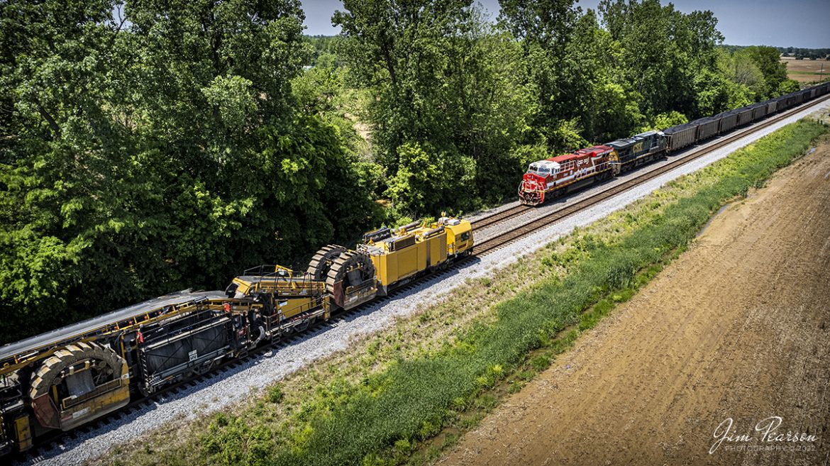 CSXT 911 leads B419 with a loaded coke train as it meets Loram shoulder ballast cleaner SBC-2401 waiting in the siding at the north end of Slaughters, Kentucky on the Henderson Subdivision on May 15th, 2022. The coke train made its way to Atkinson Yard in Madisonville, KY where it was picked up by the Paducah and Louisville Railway and taken on their line to the Calvert City Terminal at Calvert City, KY.

CSXT 911 is one of several specialty painted units that CSX has painted in the last few years and this unit honors First Responders.

The shoulder ballast cleaner removes ballast at the end of the ties, screens the ballast and discards fines and fouling material and restoring the good ballast to the shoulder. Integrated scarifiers break open end of tie mud pockets, removes fines, and restores ballast voids in the shoulders and under the tie ends and release damaging trapped water.

Tech Info: DJI Mavic Air 2S Drone, Altitude 61ft, RAW, 22mm, f/2.8, 1/500, ISO 140.

#trainphotography #railroadphotography #trains #railways #dronephotography #trainphotographer #railroadphotographer #jimpearsonphotography