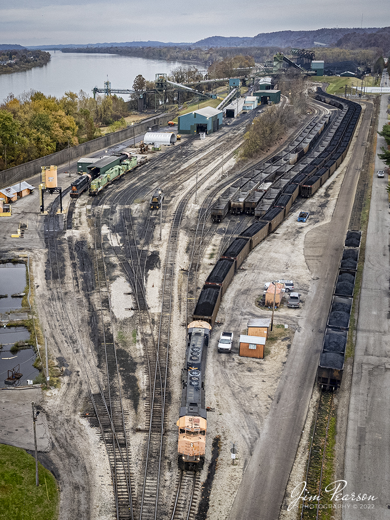 Kanawha River Terminal Railroad locomotive 1100 (GP40-2LW, built as Canadian National #9505
to Kanawha River Terminal #1100) and 1200 (GP40-2LW, built as Canadian National #9638) to Kanawha River Terminal #1100), work on moving a coal train at Ceredo, West Virginia, on November 2nd, 2022, at Kanawha River Terminal (Ceredo Dock) facility. 

According to their website: The Kanawha River Terminal Railroad is a switching operation serving the Kanawha River Terminal (Ceredo Dock) facility, situated along the Ohio River west of Huntington, West Virginia. The railroad operation handles interchange with Norfolk Southern and CSK Transportation. 

The terminal has an annual throughput capacity of nearly 20 million tons and is equipped with a rotary dumper and a barge loader, the latter of which provides volume coal loading to barges. The facility and the switching railroad are owned by SunCoke Energy. A variety of first and second-generation motive power is maintained at an engine house in Ceredo, West Virginia, adjacent to the terminal.

Tech Info: DJI Mavic Air 2S Drone, 22mm, f/2.8, 1/500, ISO 200.

#trainphotography #railroadphotography #trains #railways #dronephotography #trainphotographer #railroadphotographer #jimpearsonphotography #trainsfromtheair