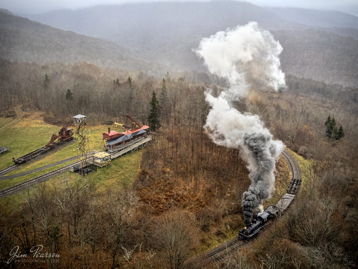 Cass Scenic Railway Shay locomotive number 11, (C-90-3) climbs into Whittaker Station, during a light rain, at the Rail Heritage Photography Weekend, at Cass, West Virginia on November 5th, 2022. In the upper left is an authentic logging camp recreated by volunteers of the Mountain State Railroad & Logging Historical Association.

According to Wikipedia: Cass Scenic Railroad, is an 11-mile (18 km) long heritage railway owned by the West Virginia State Rail Authority and operated by the Durbin and Greenbrier Valley Railroad. The park also includes the former company town of Cass and a portion of the summit of Bald Knob, the highest point on Back Allegheny Mountain.

Founded in 1901 by the West Virginia Pulp and Paper Company (now WestRock), Cass was built as a company town to serve the needs of the men who worked in the nearby mountains cutting spruce and hemlock for the West Virginia Spruce Lumber Company, a subsidiary of WVP&P. At one time, the sawmill at Cass was the largest double-band sawmill in the world. It processed an estimated 1.25 billion board feet (of lumber during its lifetime. In 1901 work started on the 4 ft 8+1⁄2 in standard gauge railroad, which climbs Back Allegheny Mountain. 

The railroad eventually reached a meadow area, now known as Whittaker Station, where a logging camp was established for the immigrants who were building the railroad. The railroad soon reached the top of Gobblers Knob, and then a location on top of the mountain known as 'Spruce'. The railroad built a small town at that location, complete with a company store, houses, a hotel, and a doctor's office. Work soon commenced on logging the red spruce trees, which grew in the higher elevations.

Tech Info: DJI Mavic Air 2S Drone, 22mm, f/2.8, 1/350, ISO 160.

#trainphotography #railroadphotography #trains #railways #dronephotography #trainphotographer #railroadphotographer #jimpearsonphotography #trainsfromtheair #trainsfromadrone