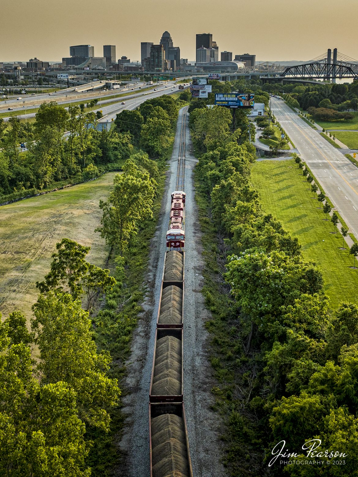 The late evening light rakes across the landscape as RJ Corman 2649 and 2645 pull Z543 out of Nugent Sand Company in Louisville, Ky, as they head toward downtown with a load of sand bound for Nugent Sand at RJ Cormans Rupp Yard in Lexington, Ky, for a variety of central Kentucky customers.

The Nugent Sand Co. at Louisville takes a million tons of sand out of the Ohio River each year. Some 400,000 to 600,000 tons of that has been moved by R.J. Corman into the Lexington and surrounding markets each year since the two companies partnered in 2005.

Tech Info: DJI Mavic 3 Classic Drone, RAW, 24mm, f/2.8, 1/240, ISO 100.

#trainphotography #railroadphotography #trains #railways #dronephotography #trainphotographer #railroadphotographer #jimpearsonphotography #CSXtrains #mavic3classic #drones #trainsfromtheair #trainsfromadrone #RJCtrain #RJCorman