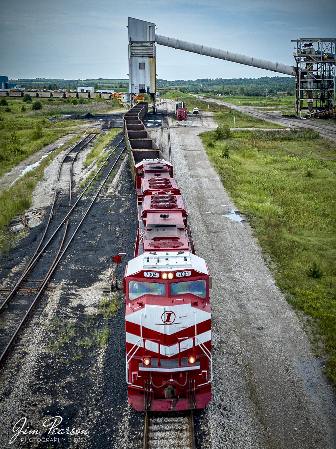 A short Indiana Railroad coal train, EHWBR (Empty Hiawatha to Bear Run) loads at Bear Run Mine, at Dugger, Indiana, on August 26th, 2023. The short load of 14 cars is destined to a customer somewhere in Wisconsin.

According to Wikipedia: The Indiana Railroad (reporting mark INRD) is a United States Class II railroad, originally operating over former Illinois Central Railroad trackage from Newton, Illinois, to Indianapolis, Indiana, a distance of 155 miles (249 km). This line, now known as the Indiana Rail Roads Indianapolis Subdivision, comprises most of the former IC/ICG line from Indianapolis to Effingham, Illinois; Illinois Central successor Canadian National Railway retains the portion from Newton to Effingham.

The company was formed in 1986 by entrepreneur Thomas Hoback, who retired as president and chief executive officer in 2015. CSX Transportation now owns a majority interest in the parent company. The company's executive and administrative offices are in downtown Indianapolis, Indiana.

Tech Info: DJI Mavic 3 Classic Drone, RAW, 24mm, f/2.8, 1/2500, ISO 180.

#trainphotography #railroadphotography #trains #railways #dronephotography #trainphotographer #railroadphotographer #jimpearsonphotography #trains #mavic3classic #drones #trainsfromtheair #trainsfromadrone #coaltrain #INRD #bearrunmine #DuggerIndiana