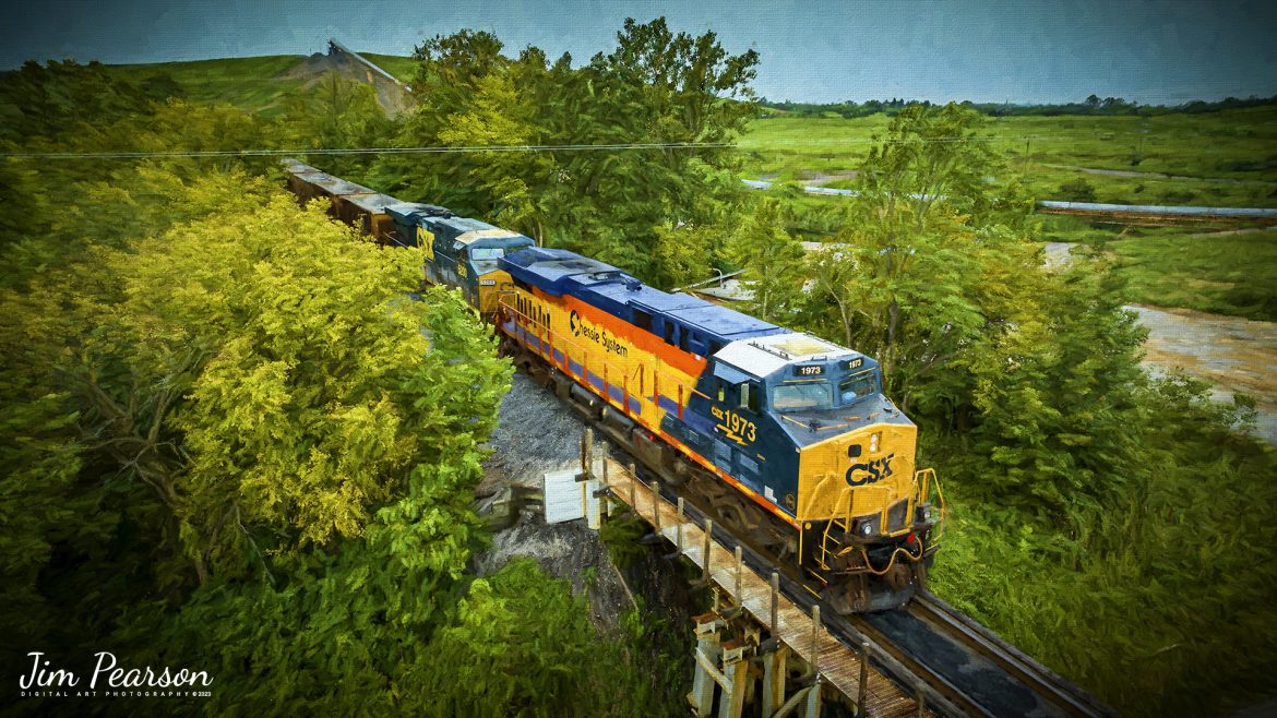 Digital Art Photo - CSX Heritage series locomotive 1973, the Chessie System unit, pulls its empty coal train up the lead, approaching the Warrior Coal Loop, outside of Nebo, Kentucky on August 13th, 2023, as it prepares to load CSX R592.

According to Wikipedia: The three railroads that would make up the Chessie System had been closely related since the 1960s. C&O had acquired controlling interest in B&O in 1962, and the two had jointly controlled WM since 1967.
Chessie System, Inc. was a holding company that owned the Chesapeake and Ohio Railway (C&O), the Baltimore and Ohio Railroad (B&O), the Western Maryland Railway (WM), and Baltimore and Ohio Chicago Terminal Railroad (B&OCT). Trains operated under the Chessie name from 1973 to 1987.

On November 1, 1980, Chessie System merged with Seaboard Coast Line Industries to form CSX Corporation. Initially, the three Chessie System railroads continued to operate separately, even after Seaboard's six Family Lines System railroads were merged into the Seaboard System Railroad on December 29, 1982. That began to change in 1983, when the WM was merged into the B&O. The Chessie image continued to be applied to new and re-painted equipment until July 1, 1986, when CSXT introduced its own paint scheme. In April 1987, the B&O was merged into the C&O. In August 1987, C&O merged into CSX Transportation, a 1986 renaming of the Seaboard System Railroad, and the Chessie System name was retired.

Tech Info: DJI Mavic 3 Classic Drone, RAW, 24mm, f/2.8, 1/320, ISO 130.

#trainphotography #railroadphotography #trains #railways #dronephotography #trainphotographer #railroadphotographer #jimpearsonphotography #trains #csxt #mavic3classic #drones #trainsfromtheair #trainsfromadrone #CSXHeritageUnits