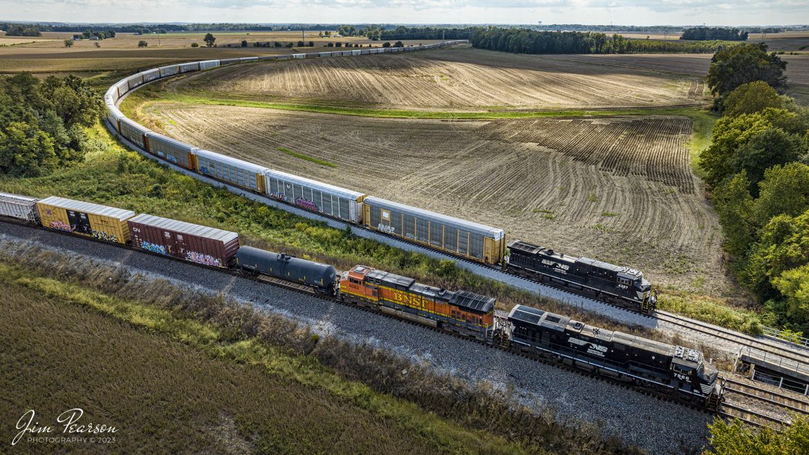 Norfolk Southern 168, with NS 7566 and BNSF 4083, mixed freight sits just short of the Height Chapel Road crossing, along with NS 4327 on the Toyota Lead, with a load of Toyotas from the plant at Princeton, Indiana, on September 28th, 2023, on the NS East District. Both trains were waiting for the yard at Princeton to clear enough for them to move.

Tech Info: DJI Mavic 3 Classic Drone, RAW, 22mm, f/2.8, 1/2000, ISO 400.

#trainphotography #railroadphotography #trains #railways #jimpearsonphotography #trainphotographer #railroadphotographer #NSTrains #PrincetonIN #dronephoto #trainsfromadrone