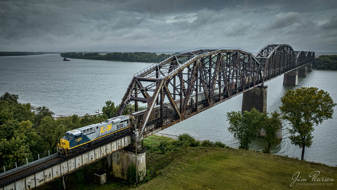 CSX loaded grain train, G419, with the latest CSX Heritage Unit, L&N 1850, heads south across the Ohio River at Henderson, Kentucky on October 5th, 2023, on the Henderson Subdivision. This bridge and trackage for the Henderson Subdivision used to belong to the Louisville and Nashville Railroad, before it was absorbed by CSX.

According to CSXT: CSX has introduced the sixth locomotive in its heritage series, a freshly painted unit honoring the Louisville & Nashville Railroad. Designated CSX 1850, the locomotive will be placed into service, carrying the L&N colors across the 20,000-mile CSX network.

The paint scheme was designed and applied at the CSX Locomotive Shop in Waycross, Georgia, which has produced all six units in the heritage series celebrating the lines that came together to form the modern CSX. Like the other heritage locomotives, the L&N unit combines the heritage railroads iconic logo and colors on the rear two-thirds of the engine with todays CSX colors and markings on the cab end.

Chartered by the State of Kentucky in 1850, the L&N grew into a vital transportation link between the Gulf Coast and the nations heartland. The railroad was absorbed by the Seaboard Coast Line Railroad, which subsequently became part of the Chessie System and, ultimately, todays CSX.

The CSX heritage series is reinforcing employee pride in the history of the railroad that continues to move the nations economy with safe, reliable and sustainable rail-based transportation services.

Tech Info: DJI Mavic 3 Classic Drone, RAW, 22mm, f/8, 1/1000, ISO 150.

#trainphotography #railroadphotography #trains #railways #jimpearsonphotography #trainphotographer #railroadphotographer #CSXHeritage #SlaughtersKy #dronephoto #trainsfromadrone #KyTrains