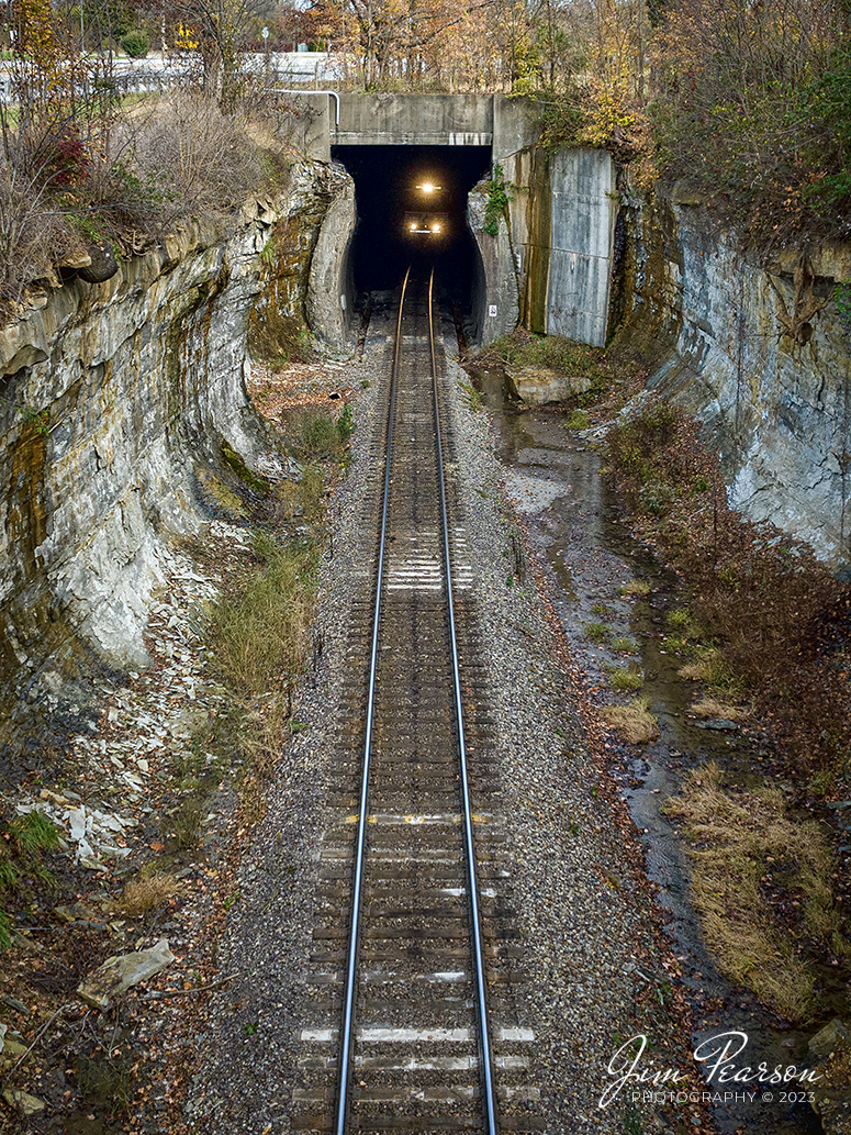 Norfolk Southern 4124 prepares to exit Duncan Hill Tunnel as it leads NS 168 westbound at Georgetown, Indiana on November 4th, 2023, on the NS Southern East District.

According to Wikipedia: The Duncan Tunnel (also known as the Edwardsville Tunnel) is a railroad tunnel in Edwardsville, Floyd County, Indiana, USA. At 4,295 feet (1,309 m) long it is the longest tunnel in Indiana, nearly a mile long. The tunnel was initially built for the Air Line, who were unable to find a suitable route over the Floyds Knobs so they decided to tunnel through them. The tunnel was completed by the Southern Railway in 1881 at a total cost of $1 million. It is currently still in use by the Norfolk Southern Railway. The tunnel passes beneath I-64 intersection #118.

Tech Info: DJI Mavic 3 Classic Drone, RAW, 22mm, f/8, 1/1000, ISO 310.

#trainphotography #railroadphotography #trains #railways #jimpearsonphotography #trainphotographer #railroadphotographer #NSRailway #DuncanHillTunnel #dronephoto #trainsfromadrone #IndianaTrains #GeorgeTownIN