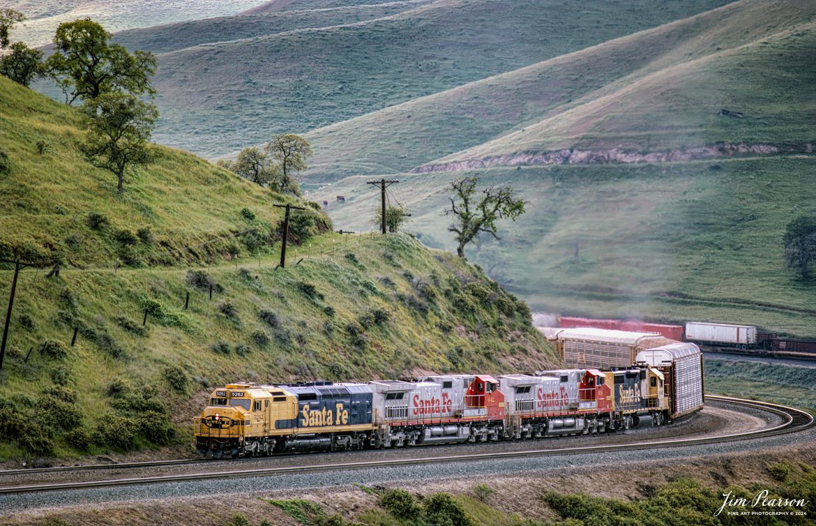 Santa Fe 5262 heads through the Tehachapi Mountains with a mixed freight on their way west along the UP Mojave Subdivision, California, in April of 1995.

According to Wikipedia: The Tehachapi Mountains are a mountain range in the Transverse Ranges system of California in the Western United States. The range extends for approximately 40 miles in southern Kern County and northwestern Los Angeles County and form part of the boundary between the San Joaquin Valley and the Mojave Desert.

The Mojave Subdivision refers to a series of railway lines in California. The primary route crosses the Tehachapi Pass and features the Tehachapi Loop, connecting Bakersfield to the Mojave Desert. East of Mojave, the line splits with the Union Pacific Railroad portion continuing south to Palmdale and Colton over the Cajon Pass and the BNSF Railway owned segment running east to Barstow. Both companies generally share trackage rights across the lines.

Tech Notes: Nikon F3 Film Camera, Nikon 300mm lens, f/stop and shutter speed not recorded