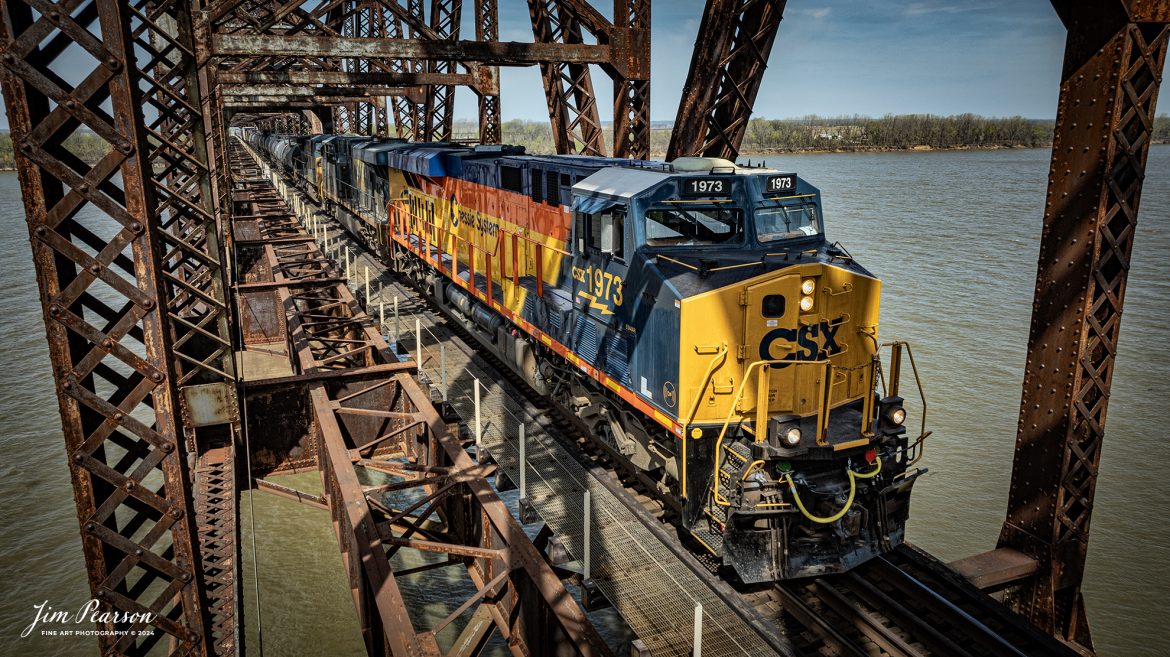 CSXT 1973, Chessie System Heritage Unit, leads CSX M647 across the Ohio River Bridge at Henderson, Kentucky, as it heads south along the CSX Henderson Subdivision, on December 22, 2023. The Henderson Subdivision has seen a lot of CSX Heritage units the last week or so and hopefully there’ll be more in the future so I can capture and share them with you! I’ll be posting some videos of these moves in future Saturday Edited Videos so keep an eye out for them!

According to Wikipedia: The three railroads that would make up the Chessie System had been closely related since the 1960s. C&O had acquired controlling interest in B&O in 1962, and the two had jointly controlled WM since 1967.

Chessie System, Inc. was a holding company that owned the Chesapeake and Ohio Railway (C&O), the Baltimore and Ohio Railroad (B&O), the Western Maryland Railway (WM), and Baltimore and Ohio Chicago Terminal Railroad (B&OCT). Trains operated under the Chessie name from 1973 to 1987.

On November 1, 1980, Chessie System merged with Seaboard Coastline Industries to form CSX Corporation. Initially, the three Chessie System railroads continued to operate separately, even after Seaboard’s six Family Lines System railroads were merged into the Seaboard System Railroad on December 29, 1982. That began to change in 1983, when the WM was merged into the B&O. The Chessie image continued to be applied to new and re-painted equipment until July 1, 1986, when CSXT introduced its own paint scheme. In April 1987, the B&O was merged into the C&O. In August 1987, C&O merged into CSX Transportation, a 1986 renaming of the Seaboard System Railroad, and the Chessie System name was retired.

Tech Info: DJI Mavic 3 Classic Drone, RAW, 22mm, f/2.8, 1/1600, ISO 110.

#trainphotography #railroadphotography #trains #railways #jimpearsonphotography #trainphotographer #railroadphotographer #csxt #dronephoto #trainsfromadrone #csx #csxheritageunit #trending