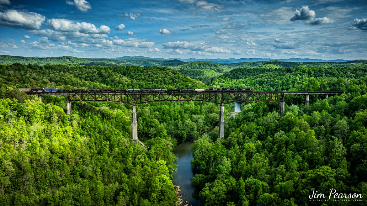 A trio of Norfolk Southern engines lead NS 168 as they make their way across the New River Bridge northbound on the NS CNO&TP (Rathole) Subdivision at New River, Tennessee. On April 29th, 2024.  

According to the Historic Bridges website: This bridge is a very large high level deck cantilever truss bridge. It was constructed in 1963 and as such is a late example of its type, but still noteworthy as an uncommon structure type and for its size. Typical of 1960s truss bridges, the bridge still has riveted built-up beams, but v-lacing and lattice are absent in the built-up beams, and truss connections are bolted instead of riveted. It is 1,622.0 Feet (494.4 Meters) long, with 3 Main Span(s) and 6 Approach Span(s) is over 300 feet above the river.

Tech Info: DJI Mavic 3 Classic Drone, RAW, 22mm, f/2.8, 1/2000, ISO 120.

#railroad #railroads #train #trains #bestphoto #railroadengines #picturesoftrains #picturesofrailway #bestphotograph #photographyoftrains #trainphotography #JimPearsonPhotography #nscnotpsubdivision #norfolksouthern #trendingphoto #nsnewriverbridge