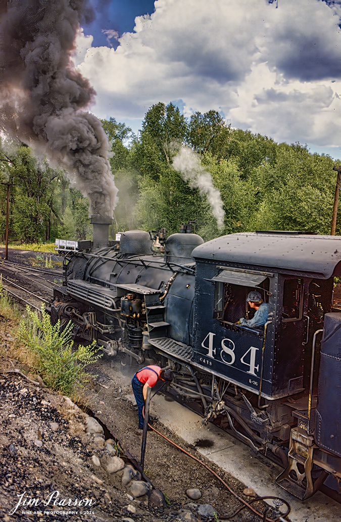 A crew on Cumbres and Toltec Scenic Railroad works on cleaning the area under the firebox after dumping the ashes from 484 at Chama, New Mexico in this shot from the early 1990's. 

According to Wikipedia: The Cumbres and Toltec Scenic Railroad, often abbreviated as the C&TSRR, is a 3 ft (914 mm) narrow-gauge heritage railroad that operates on 64 miles (103 km) of track between Antonito, Colorado, and Chama, New Mexico, in the United States. 

The railroad is named for two geographical features along the route: the 10,015-foot (3,053 m)-high Cumbres Pass and the Toltec Gorge. Originally part of the Denver and Rio Grande Western Railroad's narrow-gauge network, the line has been jointly owned by the states of Colorado and New Mexico since 1970. 

Today, the C&TSRR is one of only two remaining parts of the former D&RGW narrow-gauge network, the other being the Durango and Silverton Narrow Gauge Railroad (D&SNG), which runs between the communities of Durango and Silverton, Colorado. 

The railroad has a total of ten narrow-gauge steam locomotives (five of which are operational) and two narrow-gauge diesel locomotives on its current roster. 

The railroad also operates two smaller former D&RGW steam locomotives, Nos. 315 (owned by the Durango Railroad Historical Society) and 168 (owned by the City of Colorado Springs, Colorado), for special events and excursions.

Tech Notes: Nikon F3 Film Camera, lens, f/stop and shutter speed not recorded