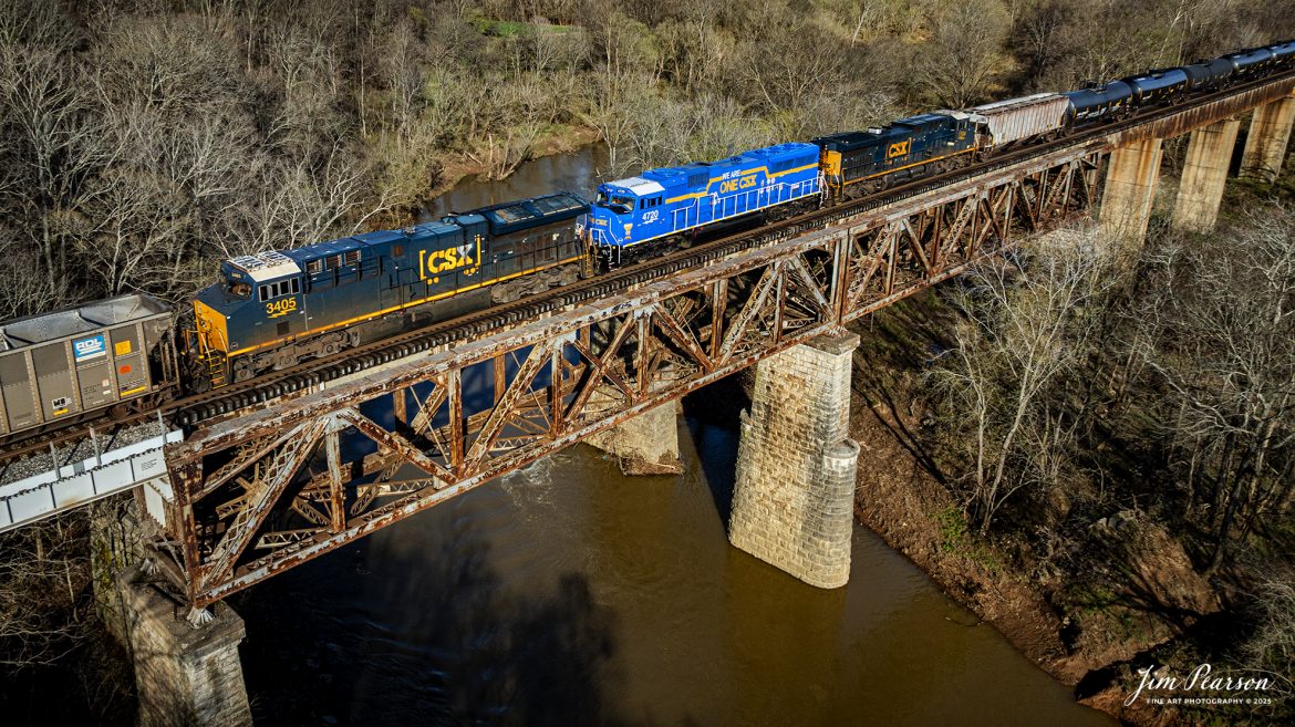 CSX E040 crosses over the Red River at Adams, TN with a combined empty coal and ethanol train (B622) and the We Are One CSX locomotive 4720 as a mid-train DPU at Guthrie, Kentucky on March 18th, 2025, on the CSX Henderson Subdivision. This is my first time catching this locomotive out in the wild and while I wish it had been leading but I’ll take what I can get!  I totally love the look of this locomotive!

According to a CSX press release, January 14, 2025 - CSX has introduced the ONE CSX locomotive, a specially designed engine to symbolize the company’s commitment to fostering collaboration, inclusion, and mutual respect across its workforce.

“This locomotive celebrates our ONE CSX team and culture,” said CSX President and Chief Executive Officer Joe Hinrichs. “I am so proud to work with 23,000 members of our ONE CSX team every day to keep America moving.”

The locomotive’s vibrant design was created by Jody Cremeans, a Carman Painter at CSX’s mechanical shop in Huntington, West Virginia. Cremeans’ design reflects the company’s cultural pillars of valuing, appreciating, including, and respecting every individual within its organization. Employees at CSX’s Waycross, Georgia, mechanical shop brought the design to life, meticulously painting and polishing the locomotive to perfection.

Prominently displayed on the locomotive are the logos of 14 labor unions that represent CSX employees, reinforcing the company’s commitment to collaboration. This special detail of the locomotive further exemplifies CSX’s focus on working together to deliver exceptional customer service while ensuring every employee feels valued and connected.

“The ONE CSX cultural initiative has been a great way for management and craft employees to come together, to work together and to value each other,” explained Jon Guest, Assistant Superintendent at the CSX Waycross Terminal.

The ONE CSX locomotive serves as a rolling tribute to the importance of teamwork and mutual respect within the organization. For CSX, its success is directly tied to creating a workplace that fosters unity and celebrates each employee’s contributions.

The new locomotive stands as a testament to the power of shared purpose within the organization and represents CSX’s aspiration to continue building an inclusive and respectful workplace.

Tech Info: DJI Mavic 3 Classic Drone, RAW, 22mm, f/2.8, 1/1250, ISO 130.

#railroad #railroads #train, #trains #railway #railway #railtransport #railroadengines #picturesoftrains #picturesofrailways #besttrainphotograph #bestphoto #photographyoftrains #bestsoldpicture #JimPearsonPhotography #trainsfromadrone #csxhendersonsubdivision #onecsx