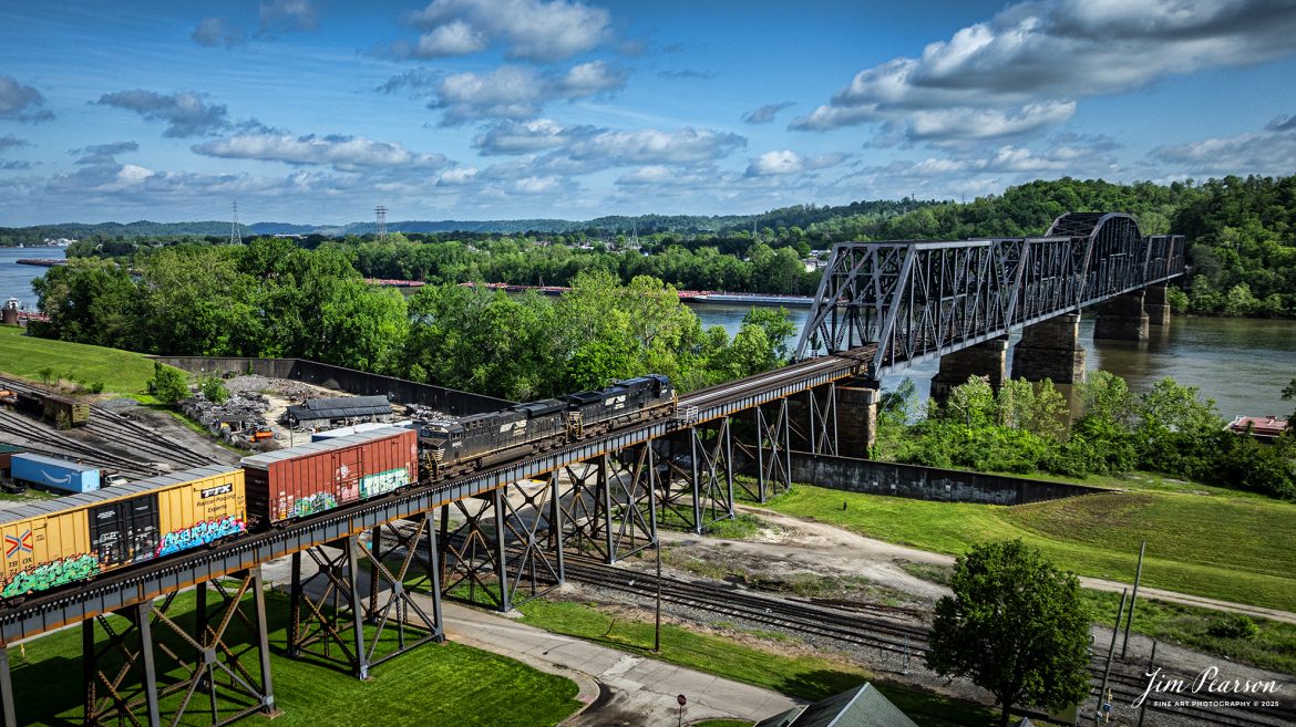 A Norfolk Southern mixed freight approaches the old N&W Bridge over the Ohio River on the Kenova District as it heads westbound at Kenova, on May 2nd, 2025.

According to Wikipedia, the bridge was first completed in 1892 with a single track, but its piers were sized for future widening. The expansion to two tracks was undertaken in 1913 by Norfolk and Western, the predecessor railway of the current owner, Norfolk Southern. The railroad added new trusses around the existing structure and expanded the piers. Rail traffic continued throughout construction, and the new tracks opened on June 9, 1913.

Tech Info: DJI Mavic 3 Classic Drone, RAW, 24mm, f/6.3, 1/2000, ISO 180.

#railroad #railroads #train, #trains #railway #railway #railtransport #railroadengines #picturesoftrains #picturesofrailways #besttrainphotograph #bestphoto #photographyoftrains #bestsoldpicture #JimPearsonPhotography #trainsfromtheair #trainsfromadrone #norfolksouthern