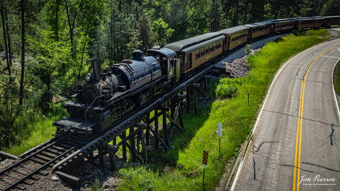 The Black Hills Central Railway locomotive 108 works their way through the Black Hills countryside as it makes its third trip of the day between Hill City to Keystone, South Dakota, on June 26th, 2025. A big shout out to Cory Jakeway for all the help on finding my way around on the railroad and railfanning with me!

According to their website: Locomotive is a 2-6-6-2T articulated tank engine that was built by the Baldwin Locomotives Works in 1926 for the Potlatch Lumber Company. It later made its way to Weyerhaeuser Timber Company and eventually to the Northwest Railway Museum in Snoqualmie, Washington.

The acquisition and subsequent restoration of locomotive 108 completed a more than 20-year goal of increasing passenger capacity which began with the restoration of 110 and the restoration of multiple passenger cars. Both large Mallet locomotives (pronounced “Malley”) can pull a full train of seven authentically restored passenger cars, up from the four cars utilized prior to their addition to the roster.

Tech Info: DJI Mavic 3 Classic Drone, RAW, 24mm, f/2.8, 1/3200, ISO 130.

#railroad #railroads #train, #trains #railway #railway #steamtrains #railtransport #railroadengines #picturesoftrains #picturesofrailways #besttrainphotograph #bestphoto #photographyoftrains #bestsoldpicture #JimPearsonPhotography #trainsfromtheair #trainsfromadrone #1880train #steamtrain #blackhills