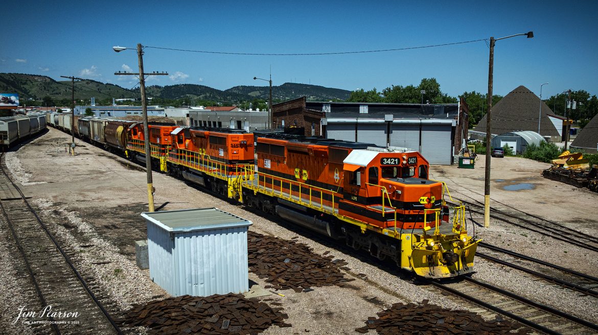 Rapid City, Pierre & Eastern Railroad (RCPE) 3421 passes their roundhouse as they head to the yard at Rapid City, South Dakota on the Black Hills Subdivision, on June 26th, 2025.

According to Wikipedia, the Rapid City, Pierre & Eastern Railroad (reporting mark RCPE) is a Class II freight railroad operating across South Dakota and southern Minnesota in the northern plains of the United States. Portions of the railroad also extend into Wyoming and Nebraska. It is owned and operated by Genesee & Wyoming. The primary commodities shipped are grain, clay, and cement. Operations began on June 1, 2014.

Genesee & Wyoming, a holding company of mostly short line railroads, formed the Rapid City, Pierre & Eastern to acquire the western end of the former Dakota, Minnesota and Eastern Railroad (DM&E) rail line from the Canadian Pacific Railway (CPR). The RCPE and DM&E entered an agreement on January 2, 2014, wherein RCPE would acquire 670 miles of track and 219 miles of trackage rights from the DM&E. The acquisition was completed on May 30, 2014, for $210 million. Most of its employees came from the DM&E.

Tech Info: DJI Mavic 3 Classic Drone, RAW, 24mm, f/5, 1/5000, ISO 100.

#railroad #railroads #train, #trains #railway #railway  #railtransport #railroadengines #picturesoftrains #picturesofrailways #besttrainphotograph #bestphoto #photographyoftrains #bestsoldpicture #JimPearsonPhotography #trainsfromtheair #trainsfromadrone #rcperailway #shortlinerailroads #southdakotarailroads