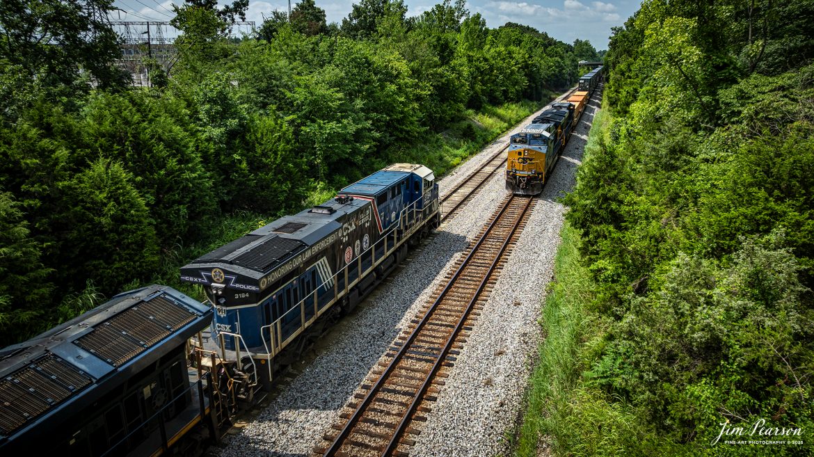 CSX I025 waits in the siding at Kelly, Ky with CSXT 3194 Law Enforcement Unit leading the way, on July 22nd, 2025, on the CSX Henderson Subdivision, as they wait for I128 NB to pass.

From a CSXT Press Release: CSXT 3194 is being renamed to honor our nation’s police officers who dedicate their lives to serve and protect communities across our network.

“CSX is proud of the employee craftsmanship involved in transforming this locomotive into a special commemorative engine,” says Ed Harris, executive vice president of operations. “This is a moving tribute to the men and women who serve us every day and aligns with CSX’s goal to connect military service members, first responders, and their families to the resources and support they need.”

The Spirit of our Law Enforcement joins our collection of Pride in Service locomotives launched this spring - the Spirit of our Armed Forces and the Spirit of our First Responders. When not actively moving customers - freight, the locomotives are made available for special events along the CSX system - extending our culture of service and commitment from our customers to the communities where we operate.

Tech Info: DJI Mavic 3 Classic Drone, RAW, 22mm, f/2.8, 1/1600, ISO 130.

#railroad #railroads #train, #trains #railway #railway #railtransport #railroadengines #picturesoftrains #picturesofrailways #besttrainphotograph #bestphoto #photographyoftrains #bestsoldpicture #JimPearsonPhotography #trainsfromtheair #trainsfromadrone