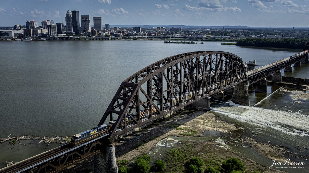 CSX M688 heads north across the Ohio River on the 14th Street Bridge (Louisville and Indiana (L&I) Bridge) at Louisville, Ky on July 28th, 2025. This bridge carries traffic for the Louisville and Indiana, along with the CSX Railroad.In the background is downtown Louisville, Ky.

According to Wikipedia: The Fourteenth Street Bridge, also known as the Ohio Falls Bridge, Pennsylvania Railroad Bridge, Conrail Railroad Bridge or Louisville and Indiana (L&I) Bridge, is a truss drawbridge that spans the Ohio River, between Louisville, Kentucky and Clarksville, Indiana.

Built by the Louisville Bridge Company and completed in 1870, the bridge was operated for many years by the Pennsylvania Railroad, giving the company its only access to Kentucky. Ownership of the railroad and the bridge passed on to Penn Central and later Conrail, which then sold the line from Louisville to Indianapolis, Indiana to the Louisville and Indiana Railroad, the current bridge owner.

The draw portion of the bridge is a vertical-lift span, built in about 1918 in place of a swing span. The towers and machinery of the lift span were designed by Waddell and Son, Inc., and there is a plaque on the SW tower reading, "Waddell Vertical Lift Bridge, Waddell and Son, 1917". The draw span is across the upstream end of the Louisville and Portland Canal, which includes the McAlpine Locks and Dam. Ohio River traffic passes through this canal to navigate past the Falls of the Ohio. 

Tech Info: DJI Mavic 3 Classic Drone, RAW, 22mm, f/2.8, 1/2500, ISO 110.

#railroad #railroads #train, #trains #railway #railway #steamtrains #railtransport #railroadengines #picturesoftrains #picturesofrailways #besttrainphotograph #bestphoto #photographyoftrains #bestsoldpicture #JimPearsonPhotography #trainsfromtheair #trainsfromadrone