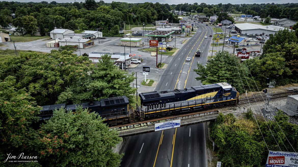 CSX empty coal train E002, with CSX Pere Marquette Heritage Unit 1899 leading, passes over East Center Street on the Henderson Subdivision cutoff at Madisonville, Ky on August 4th, 2025.

According to a CSX Press Release: May 1, 2024 – CSX has introduced the latest addition in its heritage locomotive series, paying homage to the rich history of the Pere Marquette Railroad. This new unit showcases the Pere Marquette’s legacy, dating back to its inception on November 1, 1899.

The Pere Marquette Railroad, operating in the Great Lakes region of the United States and parts of southern Ontario, Canada, derived its name from Jacques Marquette, a notable French Jesuit missionary credited with founding Michigan’s first European settlement in Sault Ste Marie. After years of operation, the company merged with the Chesapeake and Ohio Railway (C&O) on June 6, 1947, eventually becoming part of the renowned CSX network.

The design of the Pere Marquette heritage locomotive was meticulously crafted by employees at the CSX Waycross Locomotive Shop. According to CSX Carman Painter Eric Lee, “We had to measure each stripe precisely and position the words just right to ensure it captured the look of the original design. It took us about four days just to lay out the stripes before we could begin painting.”

Tech Info:Video Frame Grab from 4K DJI Mavic 3 Classic Drone, RAW, 22mm, f/2.8.

#railroad #railroads #train, #trains #railway #railway #steamtrains #railtransport #railroadengines #picturesoftrains #picturesofrailways #besttrainphotograph #bestphoto #photographyoftrains #bestsoldpicture #JimPearsonPhotography #trainsfromtheair #trainsfromadrone #paducahandlouisvillerailway #onecsx #csx