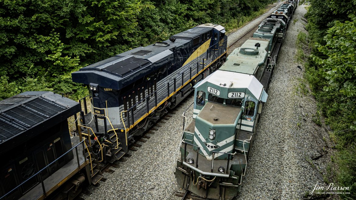CSX empty coal train E002, with CSX Pere Marquette Heritage Unit 1899 leading, waits on the main at East Diamond, as the Paducah and Louisville Railway local takes the lead heading back to their railroad after interchanging with CSX at Madisonville, Ky on August 4th, 2025.

According to a CSX Press Release: May 1, 2024 – CSX has introduced the latest addition in its heritage locomotive series, paying homage to the rich history of the Pere Marquette Railroad. This new unit showcases the Pere Marquette’s legacy, dating back to its inception on November 1, 1899.

The Pere Marquette Railroad, operating in the Great Lakes region of the United States and parts of southern Ontario, Canada, derived its name from Jacques Marquette, a notable French Jesuit missionary credited with founding Michigan’s first European settlement in Sault Ste Marie. After years of operation, the company merged with the Chesapeake and Ohio Railway (C&O) on June 6, 1947, eventually becoming part of the renowned CSX network.

The design of the Pere Marquette heritage locomotive was meticulously crafted by employees at the CSX Waycross Locomotive Shop. According to CSX Carman Painter Eric Lee, “We had to measure each stripe precisely and position the words just right to ensure it captured the look of the original design. It took us about four days just to lay out the stripes before we could begin painting.”

A fascinating tidbit related to the history of Pere Marquette is its cameo in the 2004 film “The Polar Express.” The steam locomotive Pere Marquette 1225 served as the inspiration for the train depicted in the movie, with audio recordings of the actual locomotive in operation featured in the film. Interestingly, the locomotive had been donated to Michigan State University and was exhibited near the university’s football stadium. The author of “The Polar Express” book drew inspiration from seeing this locomotive on display during childhood, solidifying its place in popular culture.

Tech Info: DJI Mavic 3 Classic Drone, RAW, 22mm, f/2.8, 1/400, ISO 110.

#railroad #railroads #train, #trains #railway #railway #steamtrains #railtransport #railroadengines #picturesoftrains #picturesofrailways #besttrainphotograph #bestphoto #photographyoftrains #bestsoldpicture #JimPearsonPhotography #trainsfromtheair #trainsfromadrone #paducahandlouisvillerailway #onecsx #csx