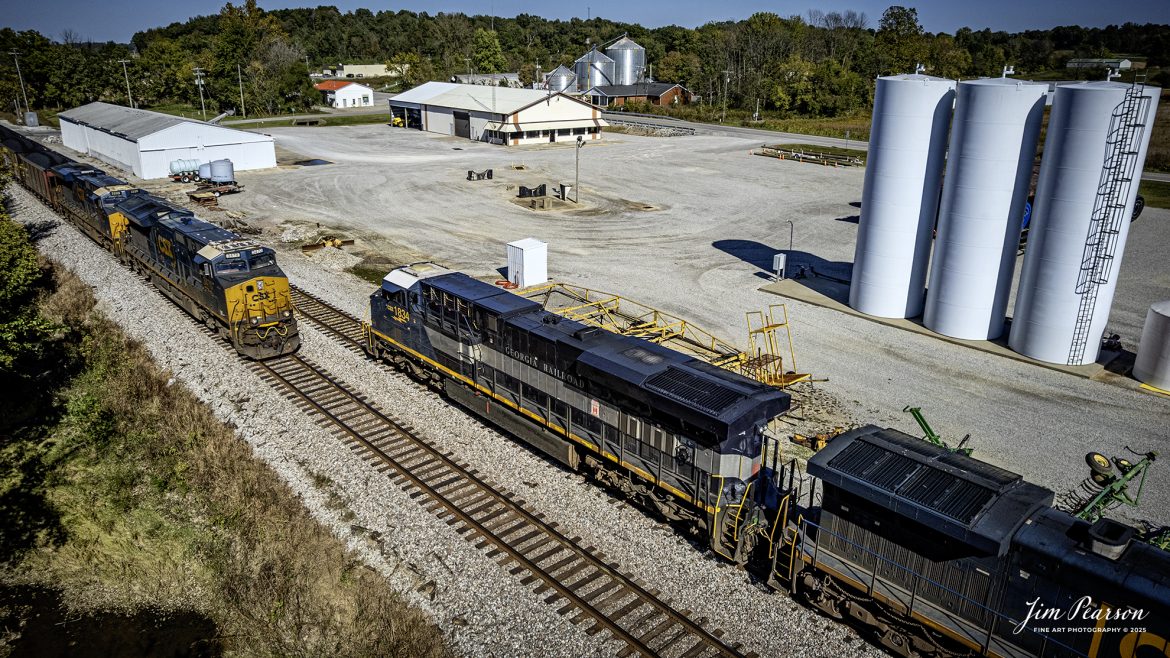 CSXT 1834 Georgia Railroad Heritage Unit leads E904 as they wait for SB C305 to pass them the north end of Slaughters, Kentucky, on October 14th, 2025, on the CSX Henderson Subdivision. 

I thought capturing this unit had finished up my goal of capturing all the current CSX Heritage Units but looking over my records I still have yet to capture the 1902 Clinchfield locomotive and so the hunt continues!

According to a CSXT Press Release: June 27, 2024 - CSX has unveiled a new heritage locomotive honoring the legacy of the Georgia Railroad. This initiative is part of CSX's ongoing efforts to recognize and pay tribute to the historic railroads that have played a pivotal role in shaping the American railway system.

The Georgia Railroad, also known as the Georgia Railroad and Banking Company, was chartered in 1833 and became one of the earliest and most influential railroads in the southeastern United States. Headquartered in Augusta, Georgia, the railroad was instrumental in facilitating transport and commerce across the region during the 19th and early 20th centuries.

Originally, the Georgia Railroad was established to connect Augusta with Athens, Georgia. Its route expanded over time, linking key cities such as Atlanta and Macon, thereby becoming an important artery for economic growth in the state. The railroad was renowned for its efficiency and reliability, transporting both passengers and freight.

In addition to its transportation services, the Georgia Railroad also had substantial banking operations, which further cemented its role as a vital institution in the region. Throughout its operational years, it underwent several mergers and partnerships, maintaining its prominence in the railway industry until it eventually became part of the CSX network.

CSX's heritage locomotive series honors the historical railroads that contributed to the company's formation. By introducing locomotives painted in the liveries of these historic lines, CSX seeks to preserve the memories and significance of these railroads while educating the public about their contributions to America's development. The newly unveiled heritage locomotive honoring the Georgia Railroad features a striking design that incorporates the classic colors and logo reminiscent of the original Georgia Railroad branding.

Tech Info: DJI Air 2S Drone, RAW, 22mm, f/2.8, 1/3200, ISO 120

#railroad #railroads #train, #trains #railway #railway #railtransport #railroadengines #picturesoftrains #picturesofrailways #besttrainphotograph #bestphoto #photographyoftrains #bestsoldpicture #JimPearsonPhotography #trainsfromtheair #trainsfromadrone #onecsx #csx