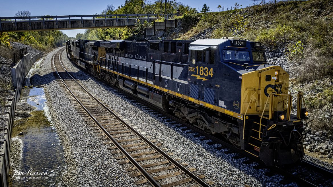 CSXT 1834 Georgia Railroad Heritage Unit leads E904 as they head north under the New Salem Loop Circle Road at Nortonville, Kentucky, on October 14th, 2025, on the CSX Henderson Subdivision. 

I thought capturing this unit had finished up my goal of capturing all the current CSX Heritage Units but looking over my records I still have yet to capture the 1902 Clinchfield locomotive and so the hunt continues!

According to a CSXT Press Release: June 27, 2024 - CSX has unveiled a new heritage locomotive honoring the legacy of the Georgia Railroad. This initiative is part of CSX's ongoing efforts to recognize and pay tribute to the historic railroads that have played a pivotal role in shaping the American railway system.

The Georgia Railroad, also known as the Georgia Railroad and Banking Company, was chartered in 1833 and became one of the earliest and most influential railroads in the southeastern United States. Headquartered in Augusta, Georgia, the railroad was instrumental in facilitating transport and commerce across the region during the 19th and early 20th centuries.

Originally, the Georgia Railroad was established to connect Augusta with Athens, Georgia. Its route expanded over time, linking key cities such as Atlanta and Macon, thereby becoming an important artery for economic growth in the state. The railroad was renowned for its efficiency and reliability, transporting both passengers and freight.

In addition to its transportation services, the Georgia Railroad also had substantial banking operations, which further cemented its role as a vital institution in the region. Throughout its operational years, it underwent several mergers and partnerships, maintaining its prominence in the railway industry until it eventually became part of the CSX network.

CSX's heritage locomotive series honors the historical railroads that contributed to the company's formation. By introducing locomotives painted in the liveries of these historic lines, CSX seeks to preserve the memories and significance of these railroads while educating the public about their contributions to America's development. The newly unveiled heritage locomotive honoring the Georgia Railroad features a striking design that incorporates the classic colors and logo reminiscent of the original Georgia Railroad branding.

Tech Info: DJI Air 2S Drone, RAW, 22mm, f/2.8, 1/1600, ISO 120

#railroad #railroads #train, #trains #railway #railway #railtransport #railroadengines #picturesoftrains #picturesofrailways #besttrainphotograph #bestphoto #photographyoftrains #bestsoldpicture #JimPearsonPhotography #trainsfromtheair #trainsfromadrone #onecsx #csx