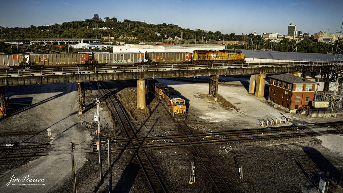 BNSF 8757 heads westbound at Santa Fe Junction as it passes under the DPU f0r a northbound Union Pacific coal train at Kansas City, KS.

Union Pacific 6180 brings up rear as DPU on an empty coal train as it heads across Santa Fe Junction on the Kansas City Terminal Railroad (KCT) High Line, while BNSF 8757 leads a westbound train past Tower #3 on October 16th, 2025.

I’m told that Santa Fe Junction sees on average over 75 trains a day and it hosts the double decked railroad (ATSF Double Deck Railroad) bridge that crosses the Kansas River into Missouri, a triple crossing in addition to Tower 3, which is used by maintenance of way these days. The junction is partly in Missouri and Kansas and sees BNSF, UP, KCT, Amtrak, KCS, NS and CP traffic, from what I saw during my visit.

According to the website railfanguides.us Santa Fe Junction Interlocking is easily the busiest location for trains in Kansas City and trains from any of the five railroads which jointly own KCT can be seen here. Tower #3 was closed in 1969 when a central dispatching center replaced it and all the other towers KCT had at the time.

The black bridge is KCT’s double deck, double track crossing of the Kansas River. The odd-looking silver towers on the bridge are lift mechanisms to raise the bridge in the event of flooding and are not connected most of the time. The upper deck line was primarily used by passenger trains from UP and Rock Island, moving to and from Kansas through the KC Union Station. Today primarily freight trains use this bridge.

The tracks through the junction have been reduced or changed around over the years, but the area remains one of KC’s Busiest locations.

Tech Info: DJI Air 2S Drone, RAW, 22mm, f/2.8, 1/1500, ISO 150

#trains #railway #JimPearsonPhotography #trainsfromadrone